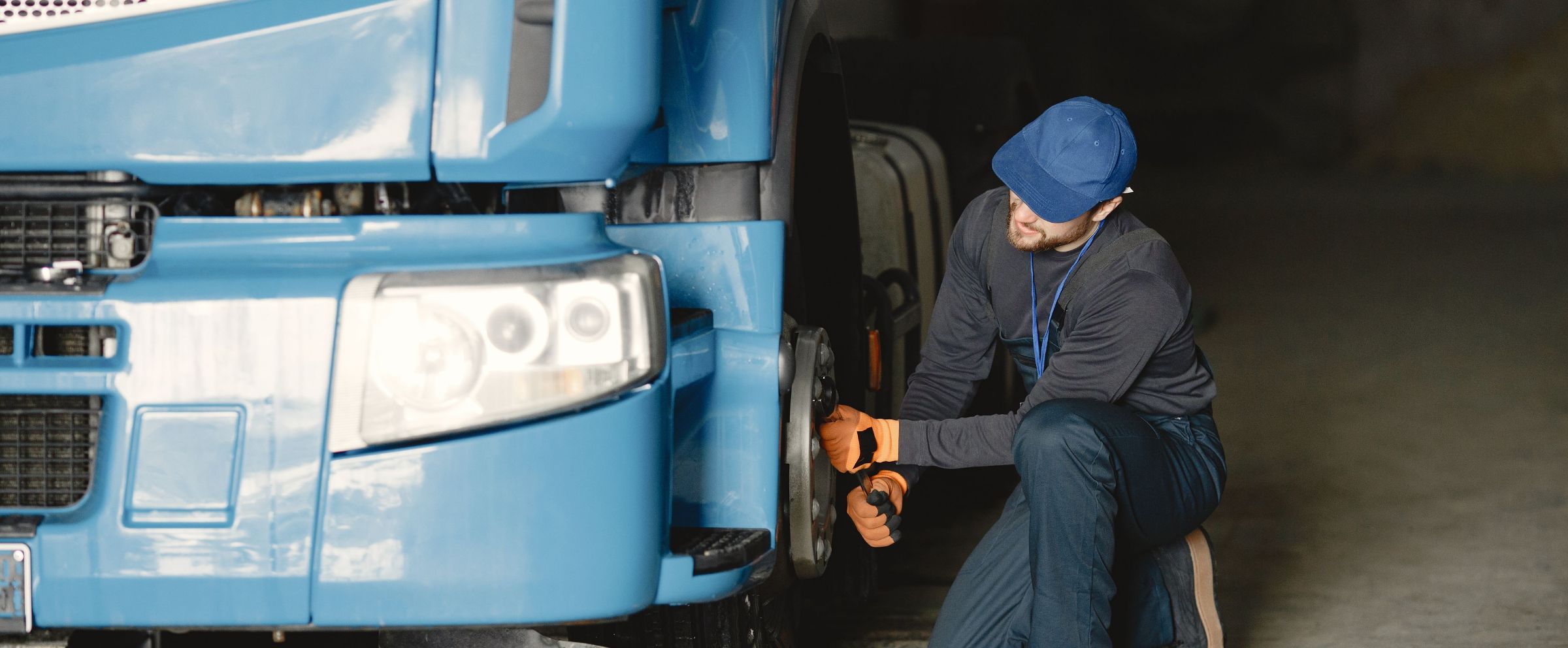 A driver checking the front wheel of a truck during a pre-start inspection